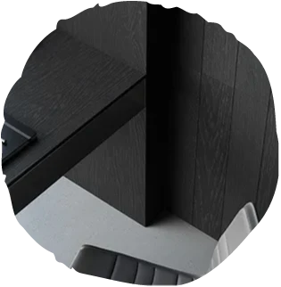 Detailní pohled na svislé dřevěné obložení stěny v dramatickém tmavém odstínu z kolekce Oakcent Ink, které v kombinaci s minimalistickou šedou podlahou a moderním nábytkem vytváří luxusní a nadčasový interiér.