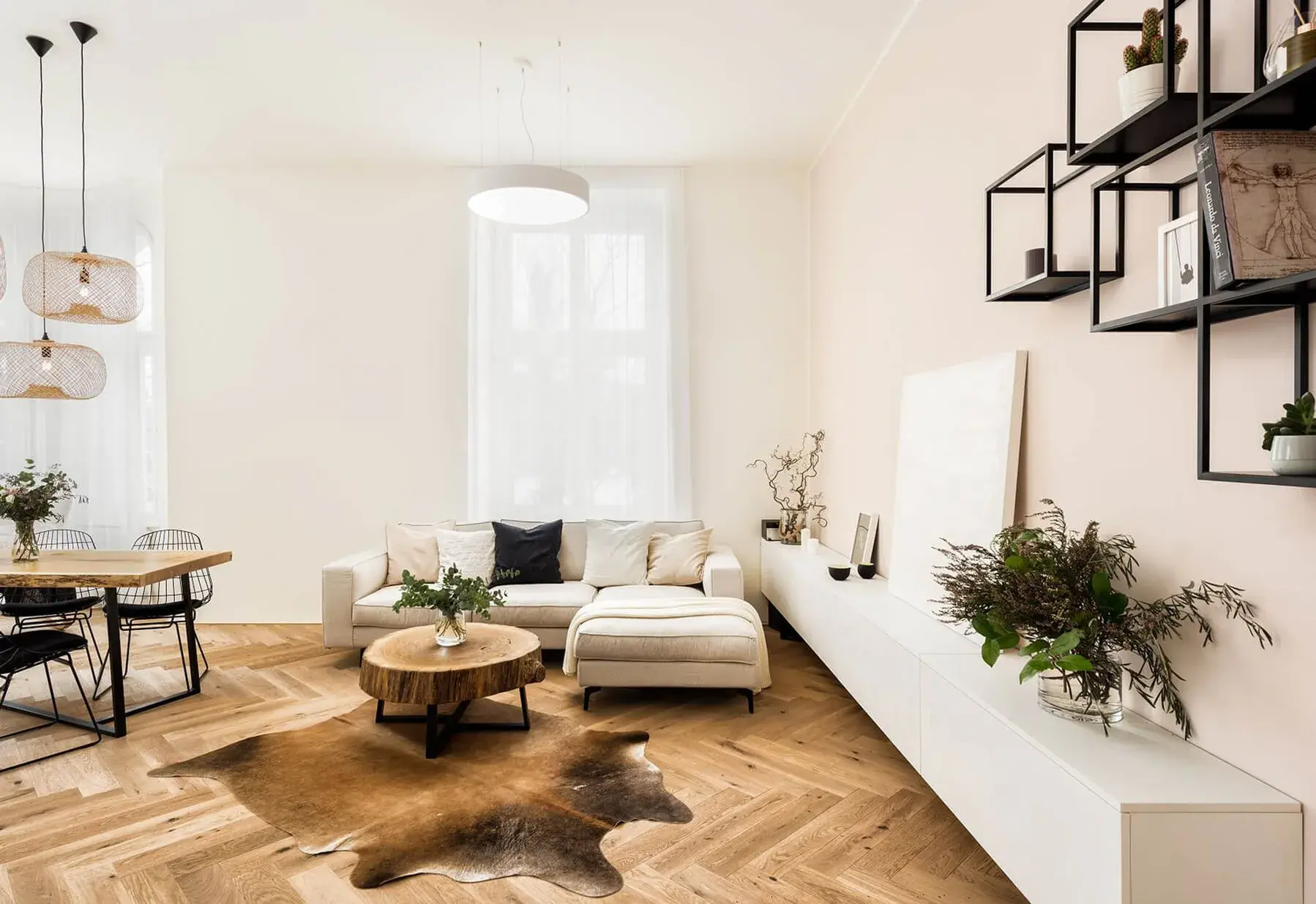 Světlý a vzdušný interiér obývacího pokoje s jídelním koutem, kterému dominuje dubová podlaha s tradičním vzorem rybí kosti (Herringbone) v přírodním odstínu, doplněná moderním nábytkem a organickými dekoracemi.